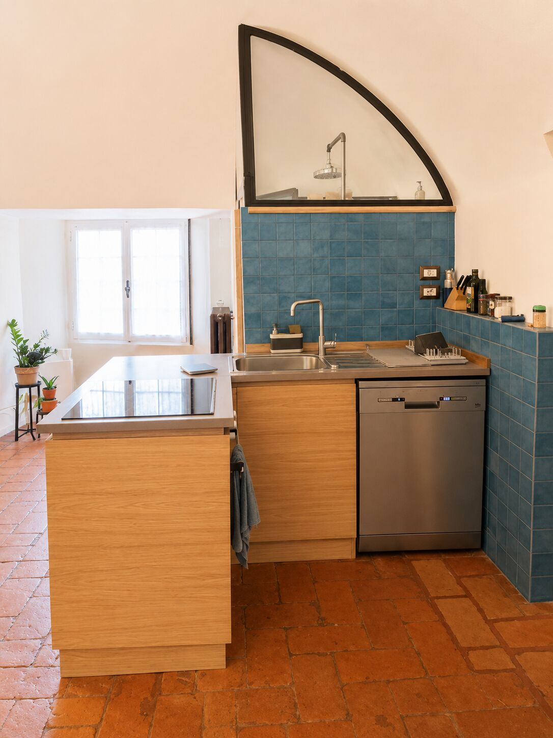 La cucina con piano a induzione, lavastoviglie e piastrelle blu